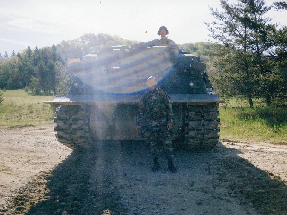 Soldiers beside a tracked armored vehicle in a wooded clearing
